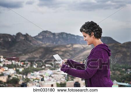 Stock Image - Caucasian woman using digital tablet on rooftop. Fotosearch