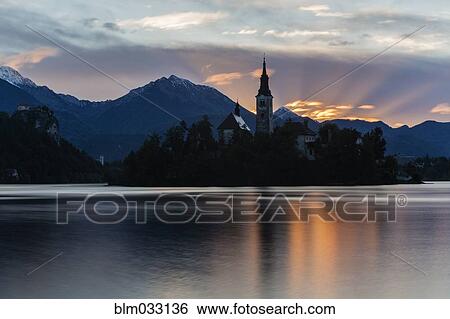 Church tower and sunrise sky reflecting in still lake View Large Photo Image Stock Photograph - Church tower and sunrise sky reflecting in still lake. Fotosearch
