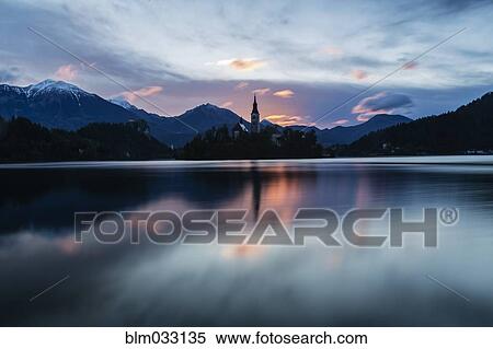 Church tower and sunrise sky reflecting in still lake View Large Photo Image Stock Photography - Church tower and sunrise sky reflecting in still lake. Fotosearch