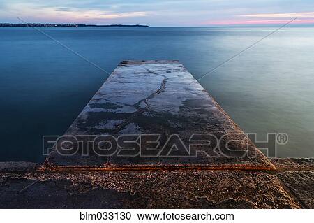 Stock Image - High angle view of concrete jetty over still ocean. Fotosearch