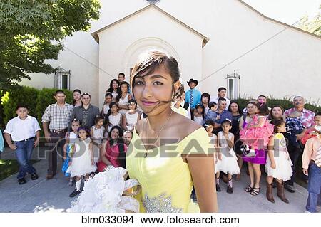 Picture - Hispanic community celebrating quinceanera outside Catholic church. Fotosearch