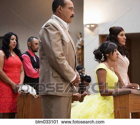 Stock Image - Hispanic family celebrating quinceanera in Catholic church. Fotosearch