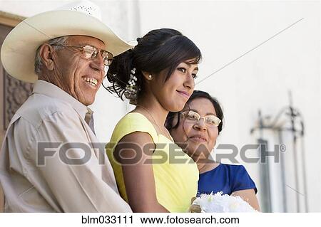 Stock Image - Hispanic family celebrating quinceanera outdoors. Fotosearch