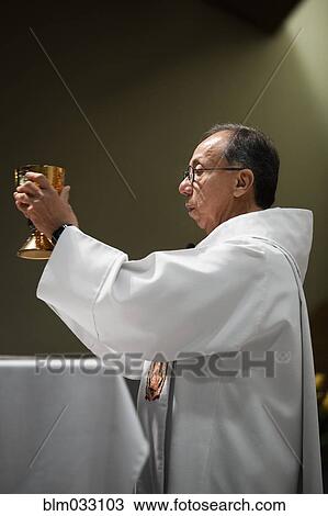 Stock Image - Hispanic priest giving sermon in Catholic church. Fotosearch