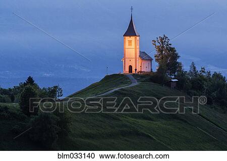 Stock Image - Illuminated church tower on remote hilltop. Fotosearch