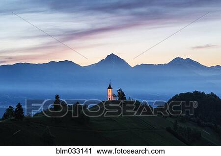 Stock Image - Illuminated church tower on remote hilltop. Fotosearch