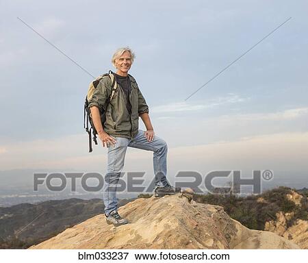 Stock Photo - Older Caucasian man standing on rocky hilltop. Fotosearch