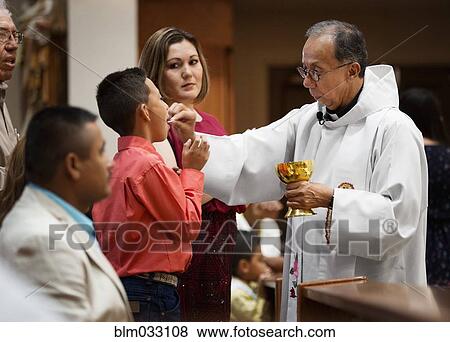 Stock Photo - Priest giving communion during mass in Catholic church. Fotosearch