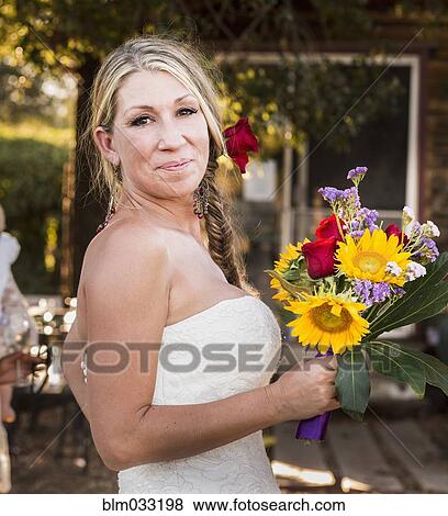 Smiling Caucasian bride holding bouquet of flowers View Large Photo Image Stock Photo - Smiling Caucasian bride holding bouquet of flowers. Fotosearch