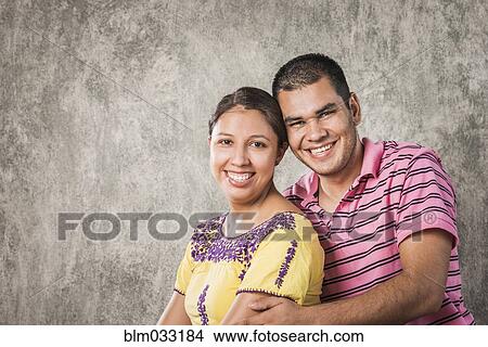 Picture - Smiling Hispanic couple hugging. Fotosearch