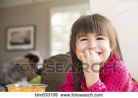 Stock Photo - Smiling Hispanic girl eating fruit. Fotosearch