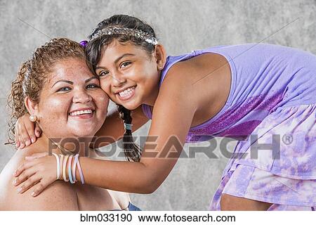 Stock Image - Smiling Hispanic mother and daughter hugging. Fotosearch