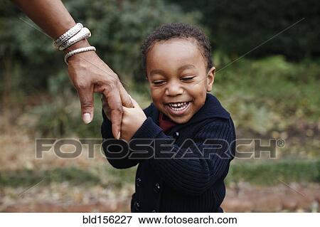 African American boy holding hand of mother in park View Large Photo Image Stock Photo - African American boy holding hand of mother in park. Fotosearch