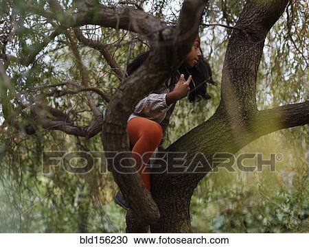 Stock Image - African American girl climbing tree. Fotosearch