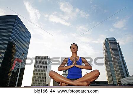 Picture - African American woman meditating on urban rooftop. Fotosearch