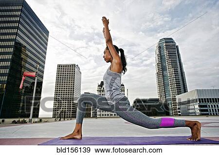 Stock Photo - African American woman meditating on urban rooftop. Fotosearch