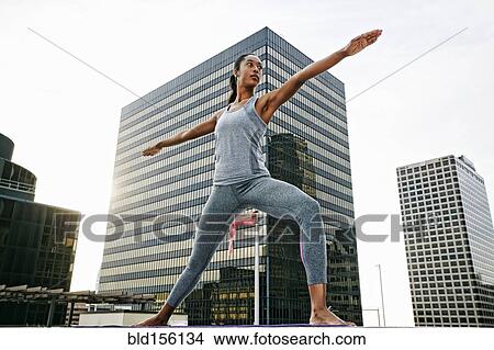 Picture - African American woman practicing yoga on urban rooftop. Fotosearch