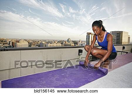 African American woman rolling yoga mat on urban rooftop View Large Photo Image Stock Photography - African American woman rolling yoga mat on urban rooftop. Fotosearch