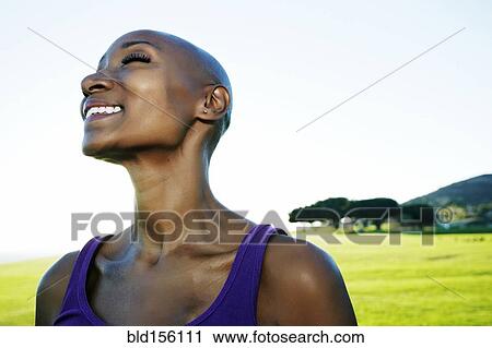 Stock Image - African American woman smiling in park. Fotosearch