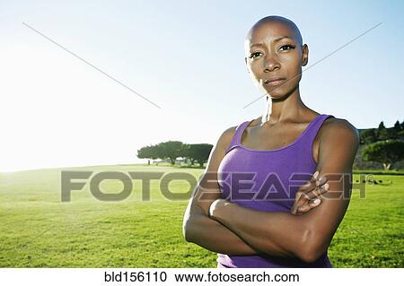 Stock Image - African American woman standing in park. Fotosearch