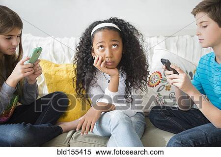 Annoyed girl ignoring friends using cell phones on sofa View Large Photo Image Stock Photography - Annoyed girl ignoring friends using cell phones on sofa. Fotosearch