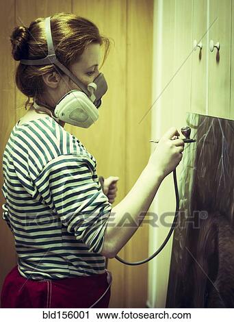 Stock Image - Artist in gas mask airbrushing painting in studio. Fotosearch