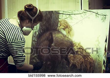 Stock Photo - Artist in gas mask airbrushing painting in studio. Fotosearch