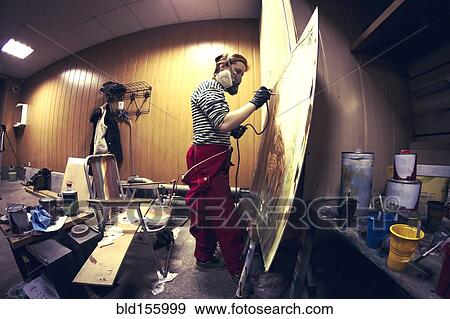 Stock Photo - Artist in gas mask airbrushing painting in studio. Fotosearch
