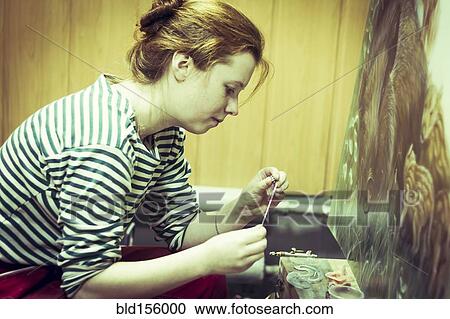 Stock Image - Artist working on painting in studio. Fotosearch