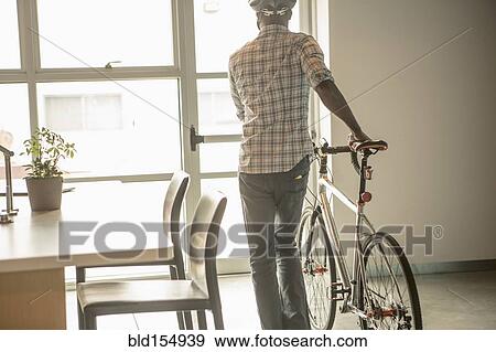 Stock Photo - Black businessman leaving office with bicycle. Fotosearch