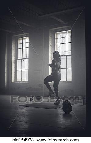 Stock Photo - Black woman exercising in dark gym. Fotosearch