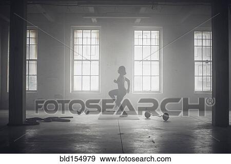 Stock Photo - Black woman exercising in dark gym. Fotosearch