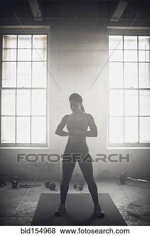 Stock Photo - Black woman standing in dark gym. Fotosearch