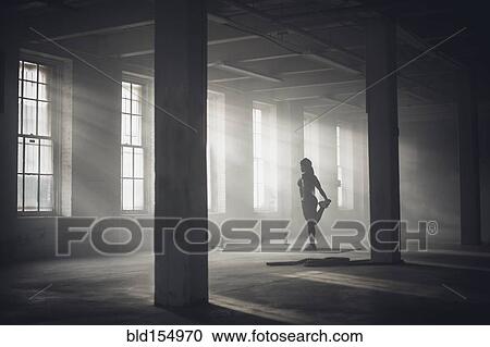 Stock Image - Black woman stretching in dark gym. Fotosearch