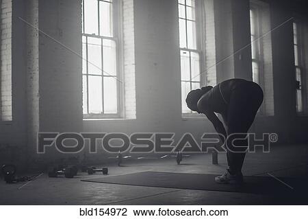 Black woman stretching in dark gym View Large Photo Image Stock Image - Black woman stretching in dark gym. Fotosearch