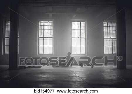 Stock Photo - Black woman stretching in dark gym. Fotosearch