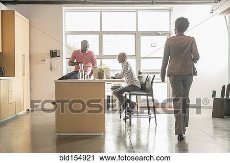 Stock Image - Business people relaxing in office kitchen. Fotosearch