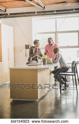 Stock Image - Business people relaxing in office kitchen. Fotosearch