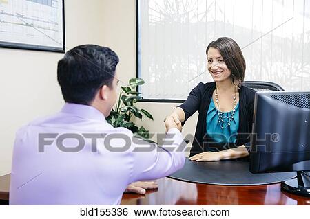 Stock Photograph - Business people shaking hands in office. Fotosearch
