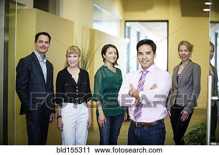 Stock Image - Business people smiling in office hallway. Fotosearch