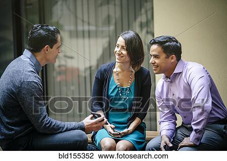 Stock Image - Business people using cell phone in office courtyard. Fotosearch