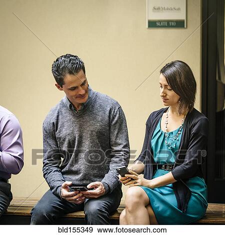 Stock Photo - Business people using cell phones in office courtyard. Fotosearch