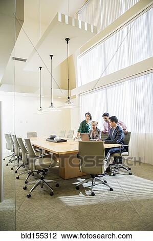 Stock Image - Business people using laptop in office meeting. Fotosearch