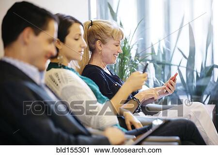 Stock Image - Business people waiting in office lobby. Fotosearch