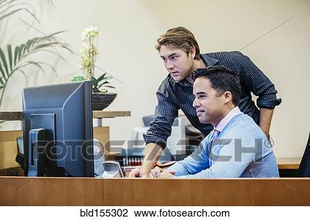 Businessmen working at computer in office lobby View Large Photo Image Stock Image - Businessmen working at computer in office lobby. Fotosearch