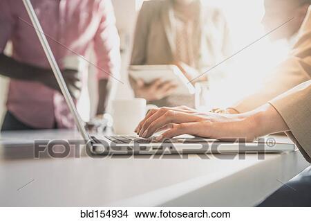 Picture - Businesswoman using laptop in office. Fotosearch