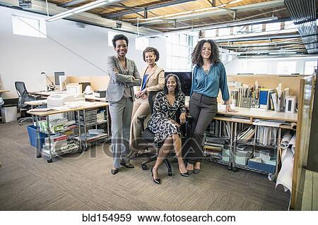 Businesswomen smiling at desk in office View Large Photo Image Stock Photo - Businesswomen smiling at desk in office. Fotosearch
