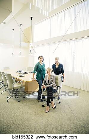 Stock Image - Businesswomen smiling in office meeting. Fotosearch
