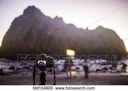 Stock Image - "Camera on self-timer taking photograph of couple on beach, Big Sur, California, United States". Fotosearch