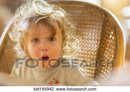 Stock Image - Caucasian baby boy gasping in wicker chair. Fotosearch